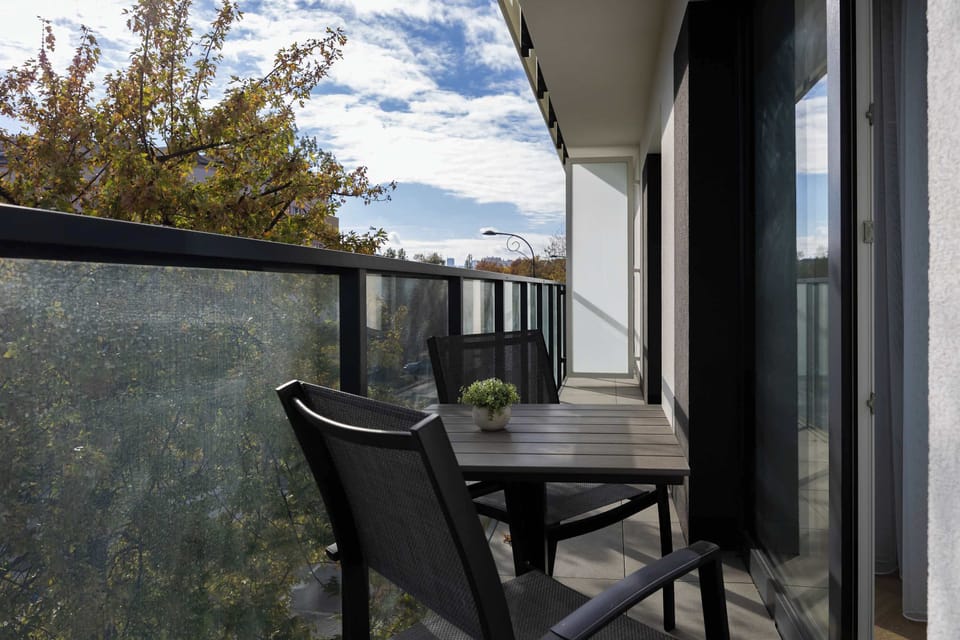 The balcony with a comfortable seating set and a view of greenery is the perfect spot for a morning coffee or an evening rest.