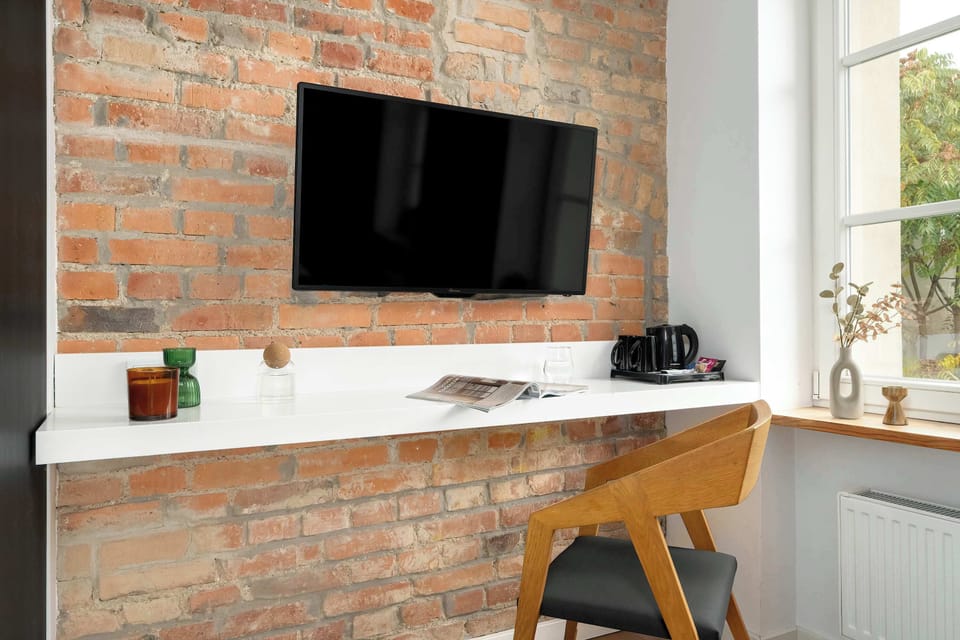 Functional workspace with a desk, TV, and large wardrobe. The big window fills the room with natural light — perfect for work or relaxation.