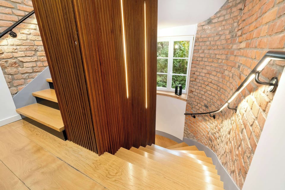 Staircase area combining brick, wood, and modern lighting.