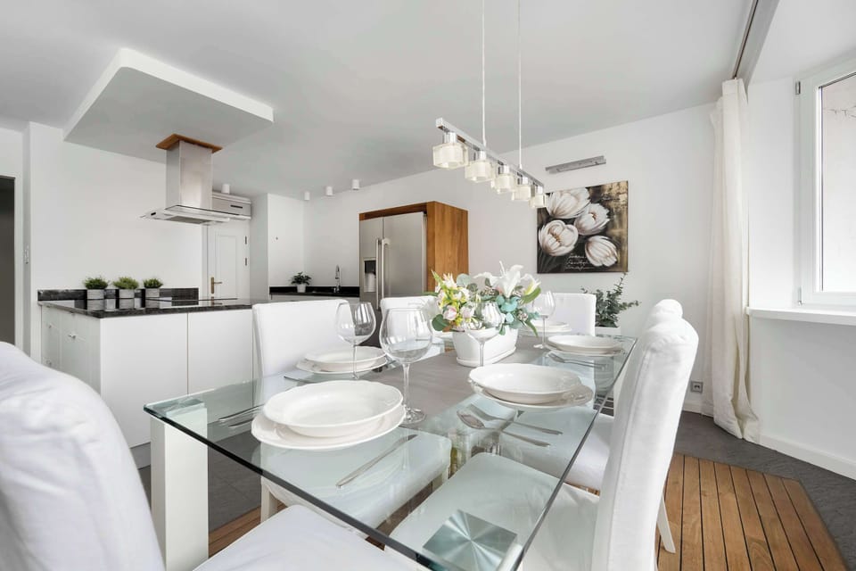 A stylish open-plan living and dining area featuring a dining table with white chairs.