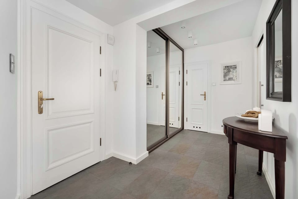A hallway with modern interior design, including a small desk and white walls.