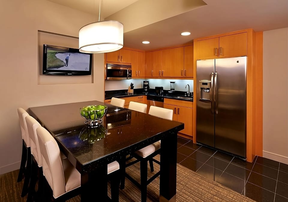 Gather for meals around a sleek table beside full kitchen.