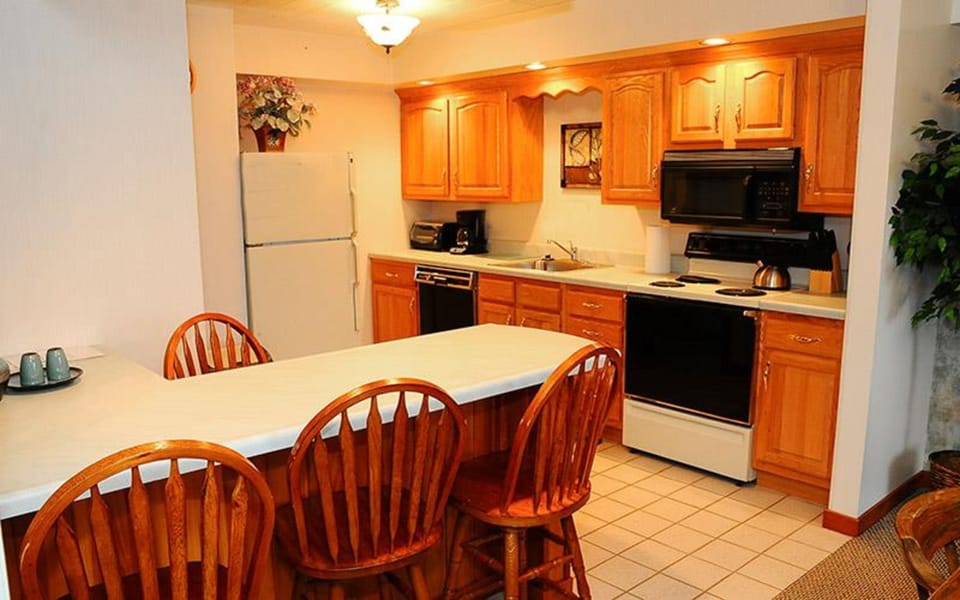 This well-equipped kitchen features warm wooden cabinetry, modern appliances, and a convenient breakfast bar with seating for casual dining.