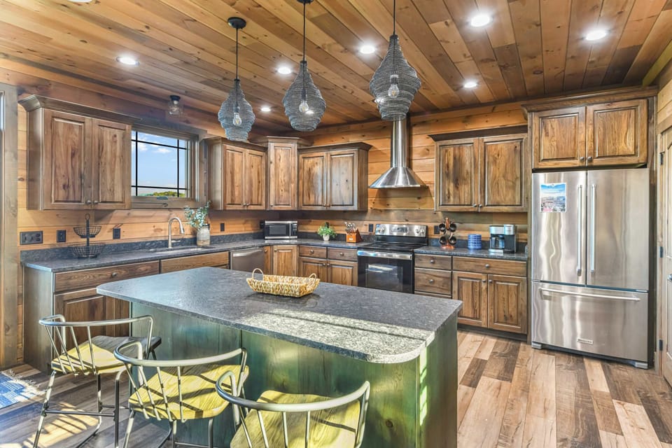 Rustic kitchen with wooden cabinetry, a large island, and stainless steel appliances.
