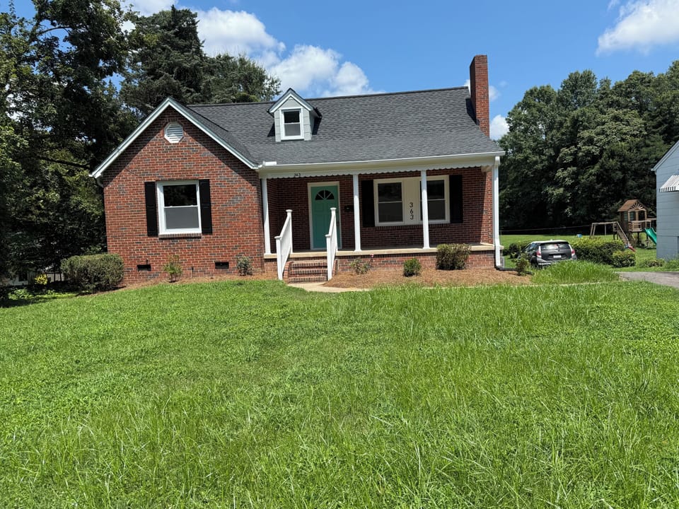 Front of the house.The shutters are now white.  Spacious front yard.  