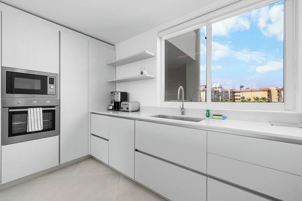 Modern, fully-equipped kitchen with sleek counters, built-in appliances, and sunny windows overlooking the neighborhood—ready for your culinary adventures.