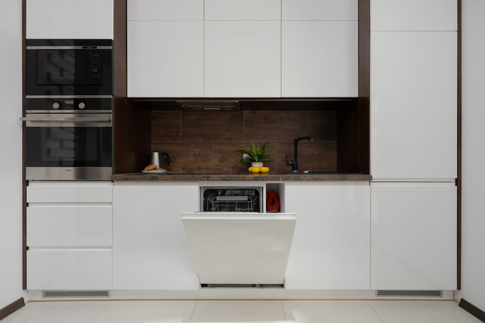 The white kitchen cabinets with a dark accent wall add a modern and elegant touch to the interior.