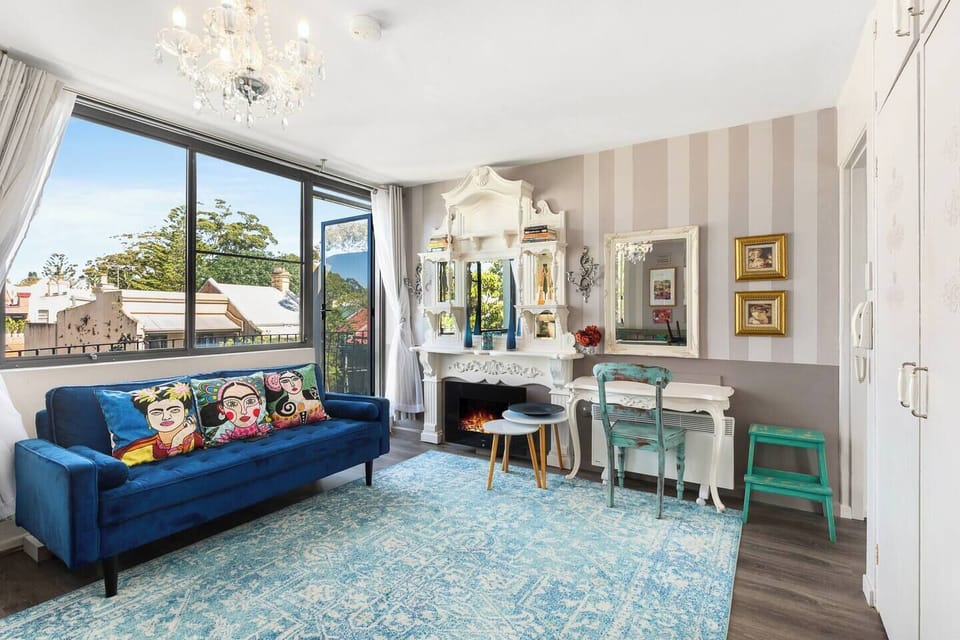 Settle into the plush blue velvet sofa beside curated artwork and warm light, a serene space to unwind after exploring Glebe.