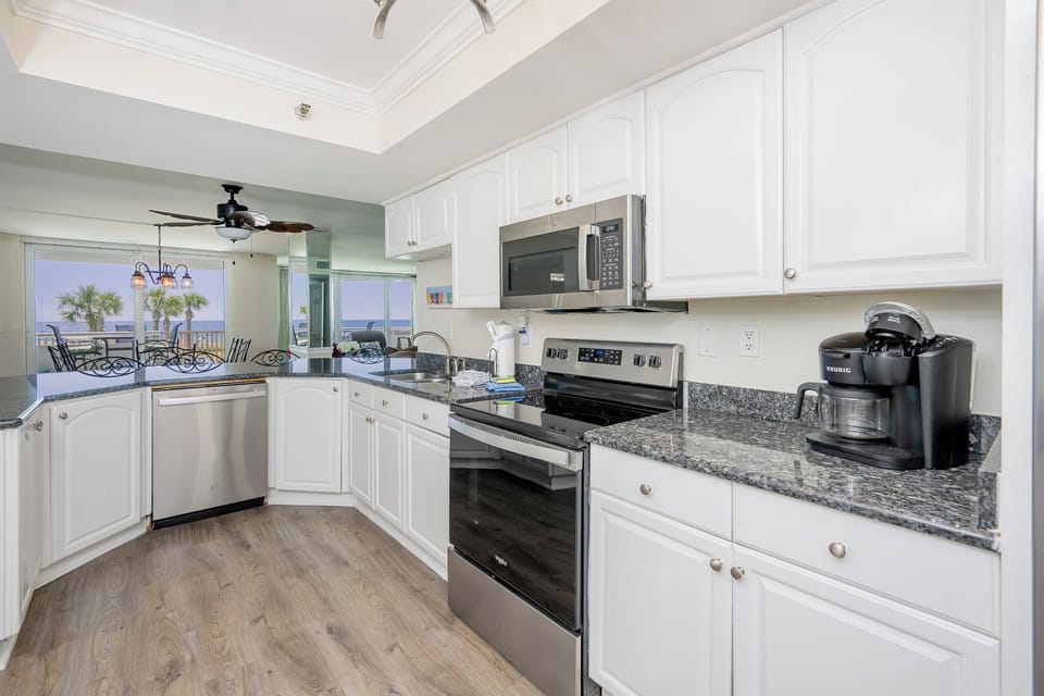 Kitchen featuring stainless appliances, granite countertops, Keurig coffee maker, and a view of the beach