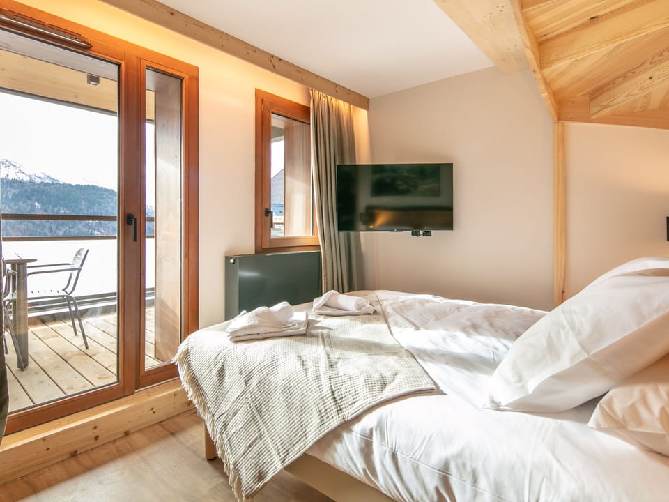 Relax in the cozy bedroom, complete with natural wood accents and easy outdoor access.