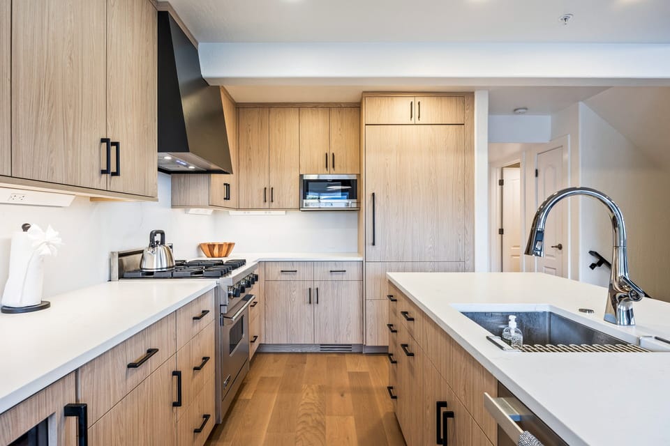 This beautifully appointed kitchen features custom wood cabinetry, high-end stainless steel appliances, and sleek quartz countertops