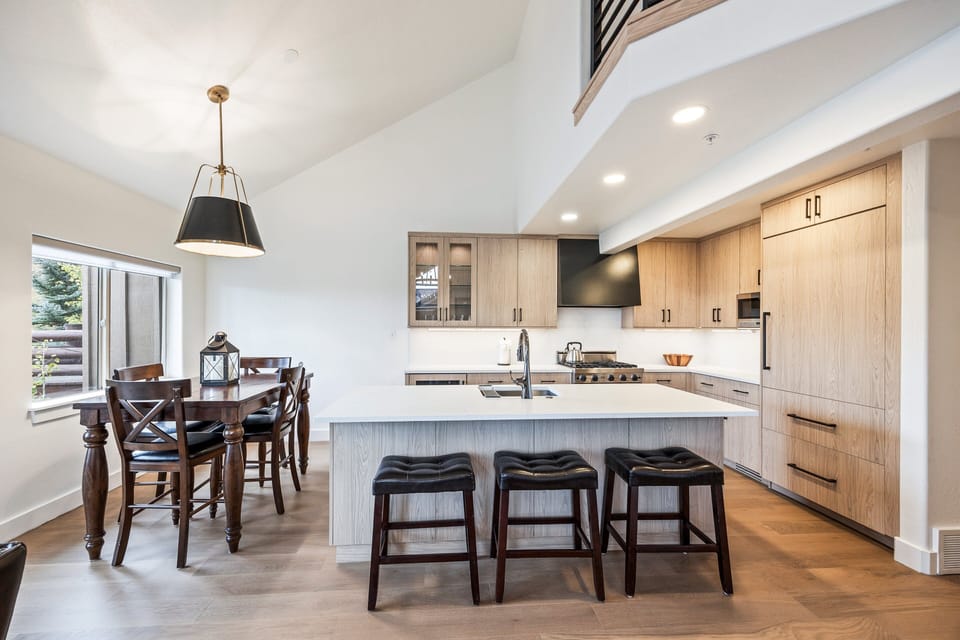 An open-concept kitchen and dining space featuring sleek cabinetry, a spacious island with seating, and modern lighting. Perfect for enjoying meals together or entertaining with views of the surrounding mountains.