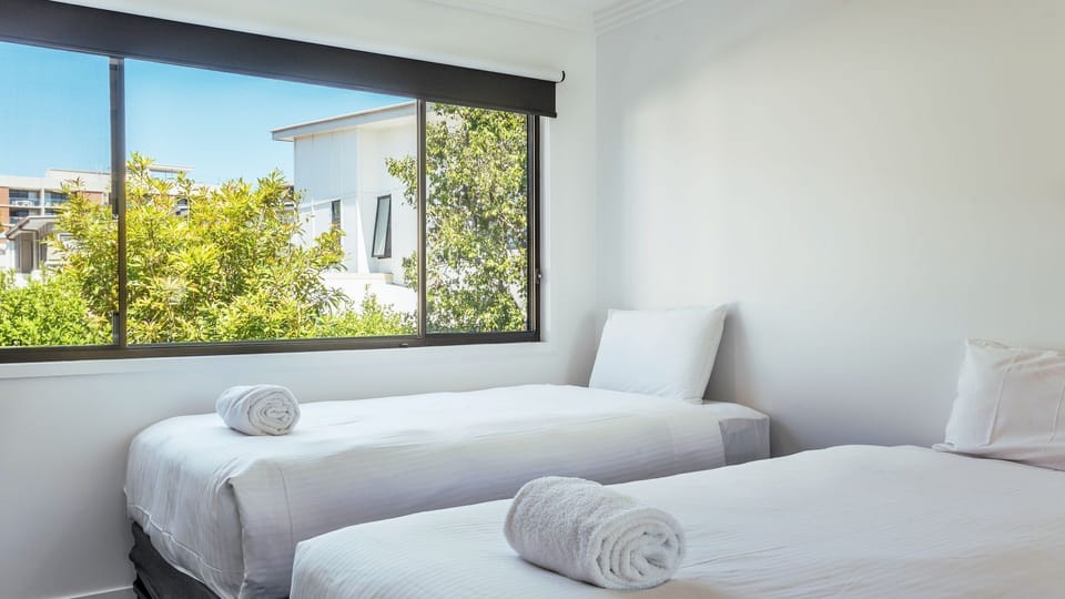 Twin bedroom with large window and natural light.