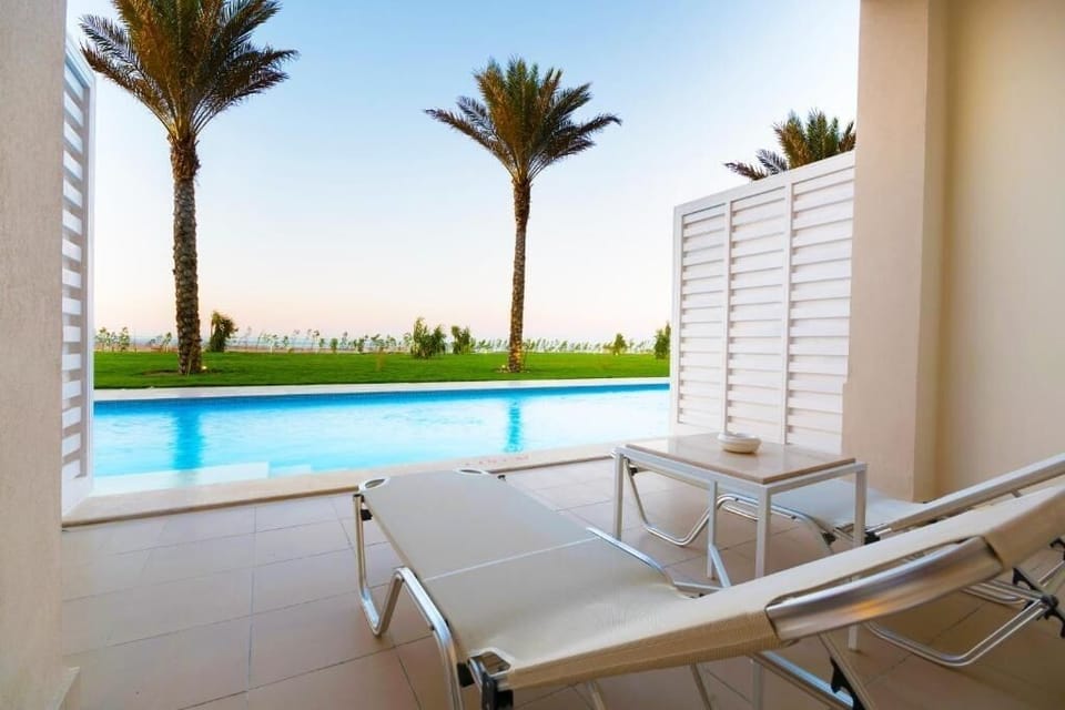 Unwind poolside with sun loungers and breezy palm views.