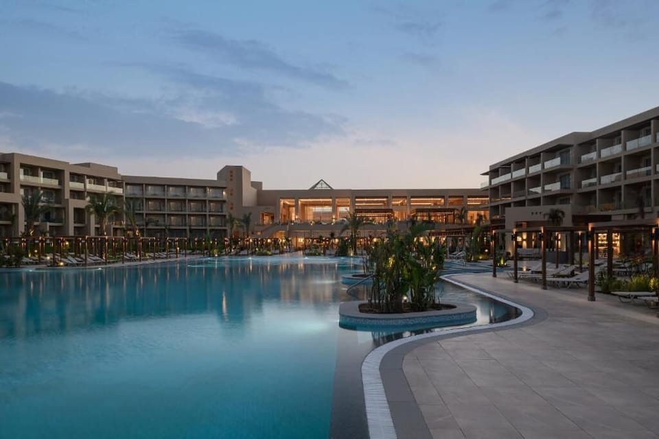 Unwind at dusk as lights sparkle across the calm lagoon pool.