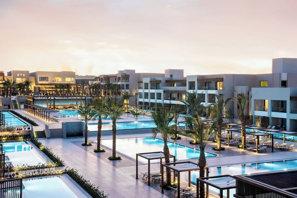 Unwind at sunset beside sparkling pools and palm silhouettes.