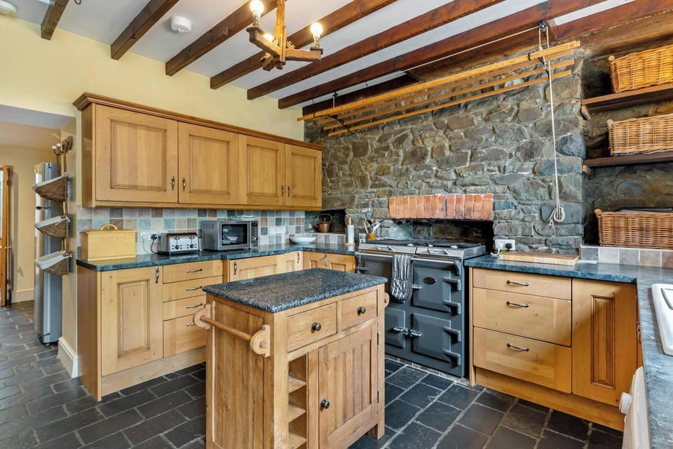Fitted pine kitchen: Aga, microwave, toaster and butchers block in centre of kitchen
