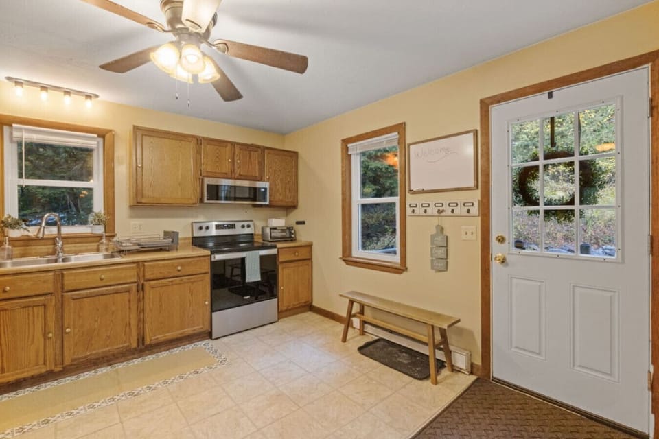 Bright, fully equipped kitchen with forest views and direct access to the deck.