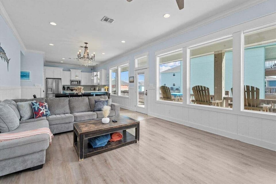 Large open living room with sectional sofa and panoramic windows offering natural light and coastal charm.