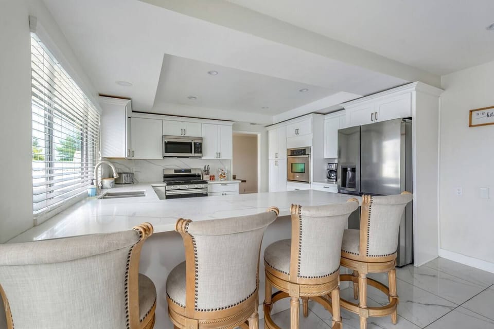 Modern, fully equipped kitchen with stainless steel appliances, spacious countertops, and seating for casual dining.