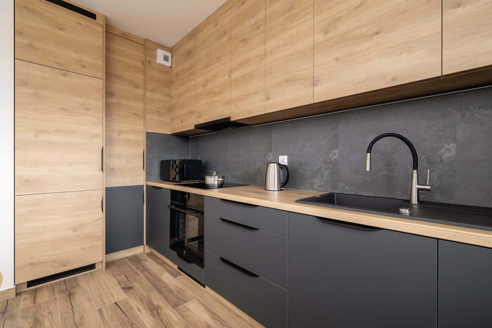 A contemporary kitchen featuring dark cabinets, a wooden countertop, and integrated appliances.