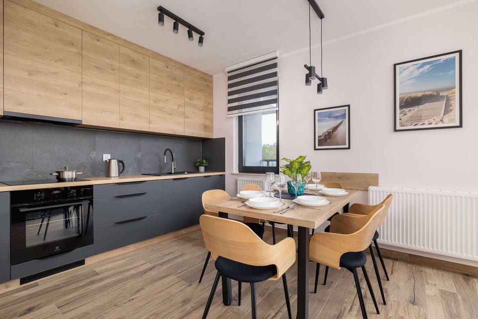 A kitchen and dining space with dark lower cabinets, light upper cabinets, and a simple wooden dining set.