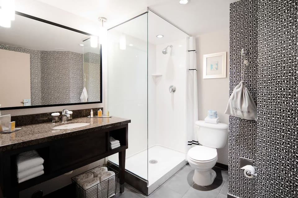 Refresh in a spotless bath with glass shower and plush towels.