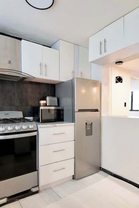 Compact and well-designed kitchen featuring stove, microwave, and fridge for a seamless and comfortable stay.