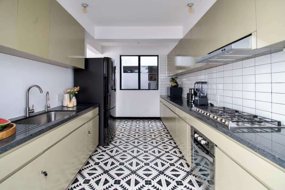 A modern galley kitchen designed for both style and function. Sleek cabinetry, patterned floors, and a full suite of stainless-steel appliances create a space that’s elegant, practical, and ready for any culinary moment.