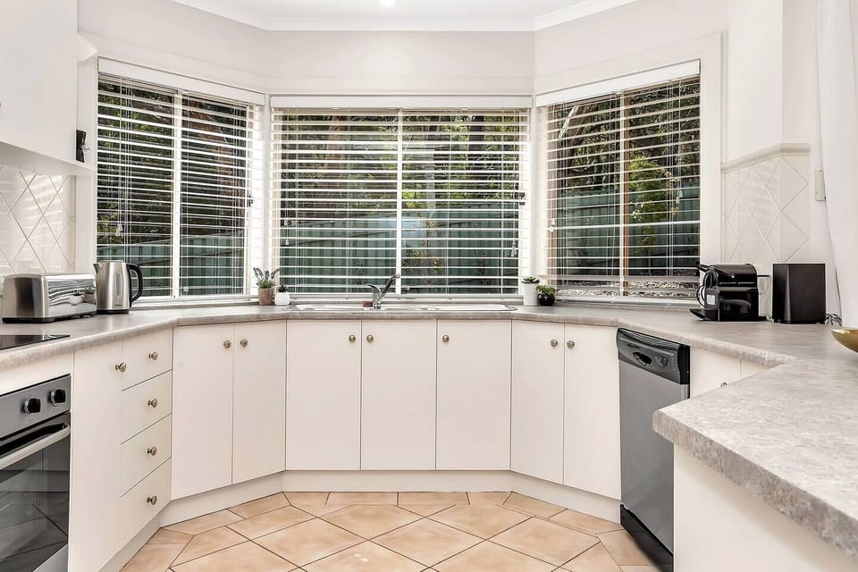 The bright open-plan kitchen offers stainless-steel appliances, an espresso machine, and ample bench space for effortless home cooking.