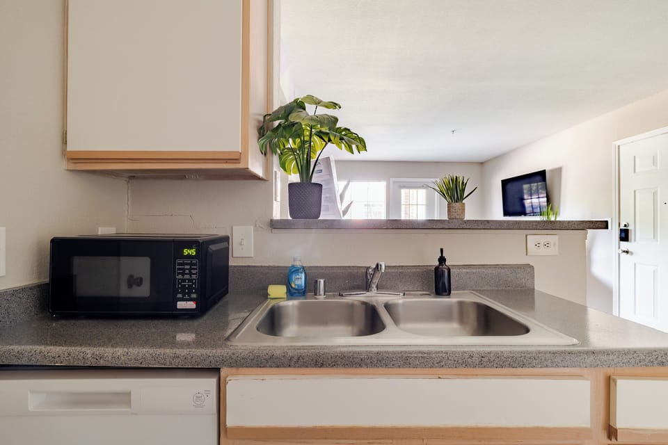Bright open kitchen with double sink, microwave, and airy pass-through