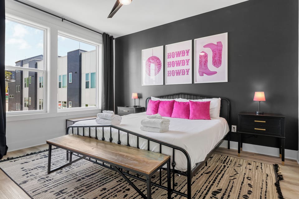 Chic bedroom with a king bed, vivid pink accents, and modern artwork.