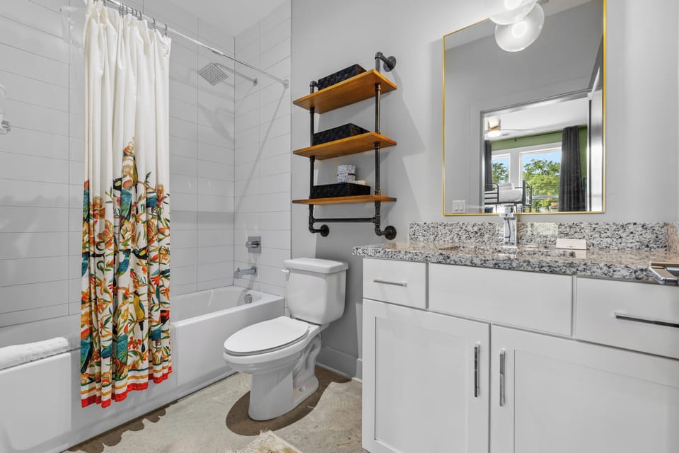 Bright full bathroom with a tub-shower, vanity, and playful curtain.