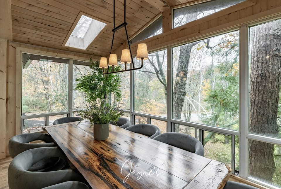 Sunlit screened dining area with rustic wood table and forest views