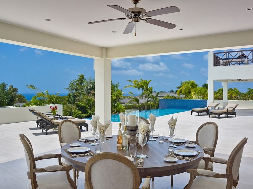 Outdoor dining area with round table for six, ceiling fan, and ocean views