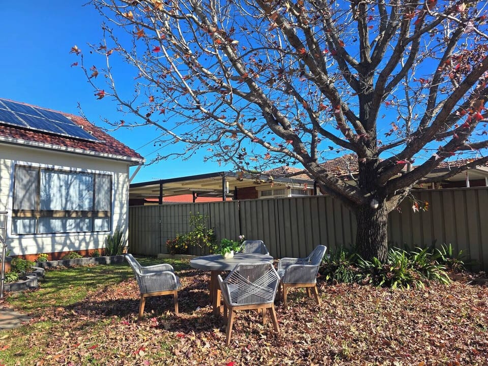 Charming front garden dining area under a beautiful deciduous tree — open for all guests to enjoy.