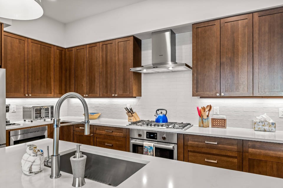 The space features custom dark wood cabinetry contrasted with crisp white quartz countertops and a modern subway tile backsplash