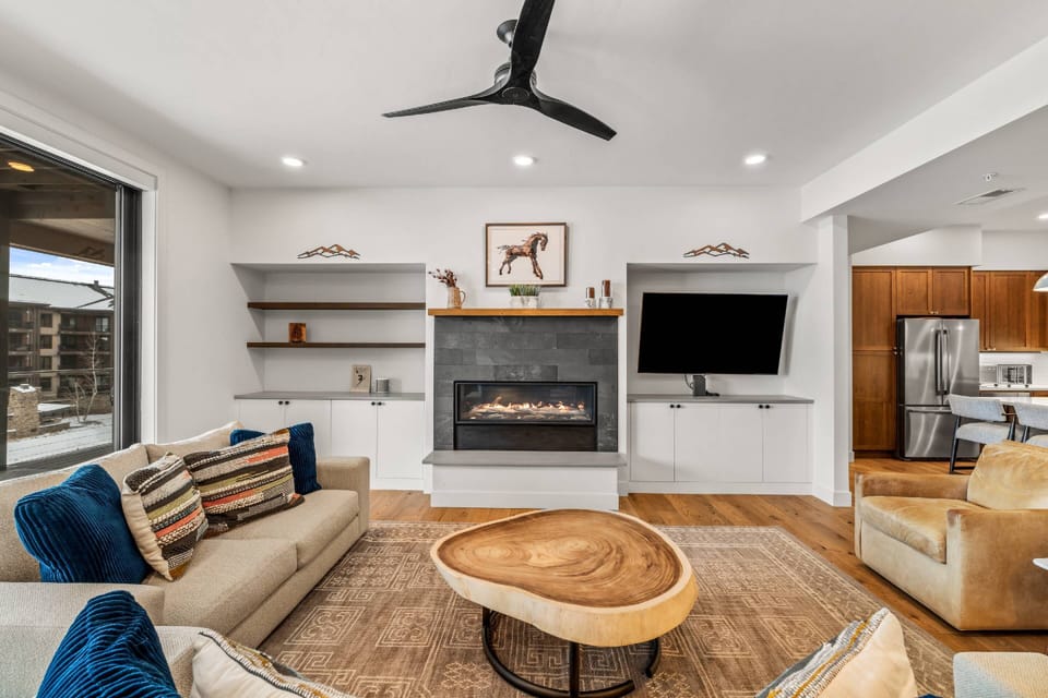 Large, light-colored sectional sofa is paired with two cognac leather armchairs, providing ample seating for gathering