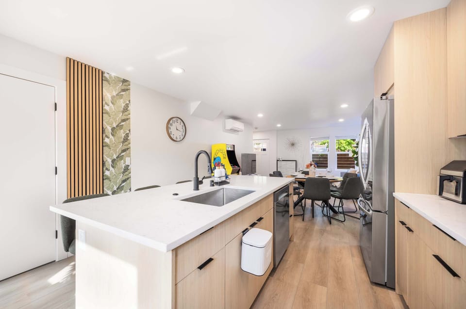 Open-Concept Kitchen – Modern kitchen with sleek light wood cabinetry, large island, and bar seating for casual meals.