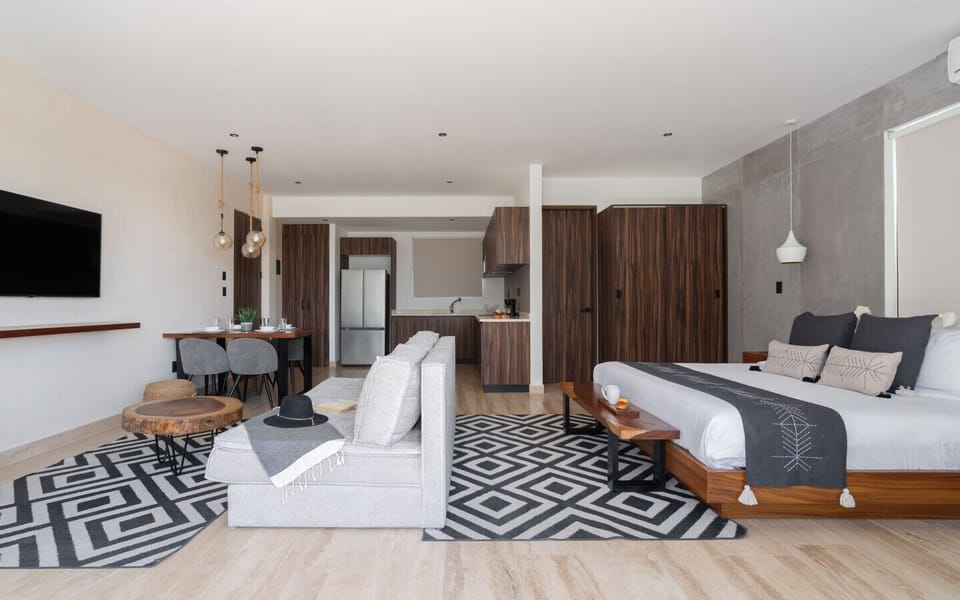 Modern open apartment with king bed, kitchen, and dining area.