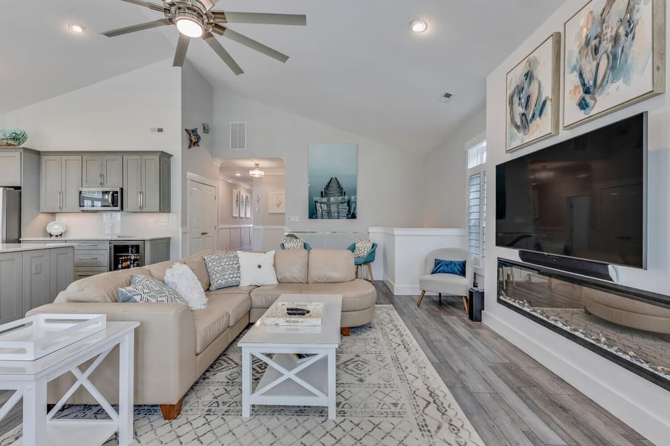 Relax in your bright, open living space with modern fireplace, ceiling fan, and stylish coastal decor creating the perfect home-away-from-home.