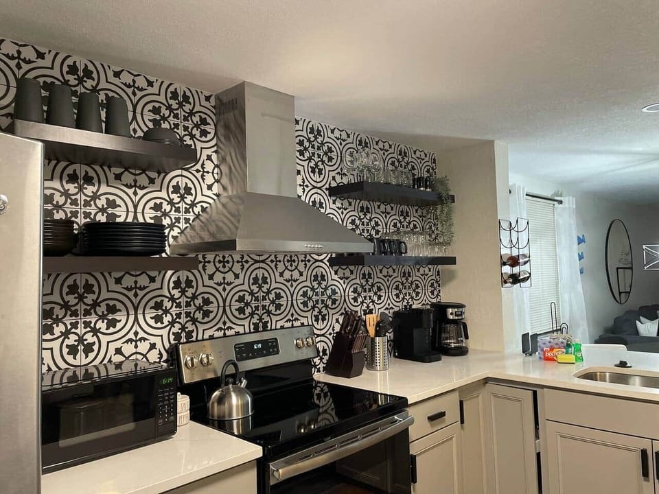 Stylish kitchen with tile, floating shelves, and a modern stainless vent hood.