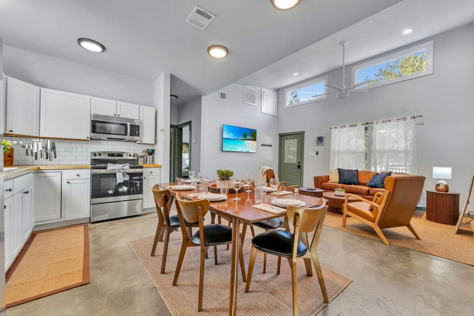 Bluebonnet Lodge full kitchen with 6 person dining table, comfy couch and chairs next to a 65` TV