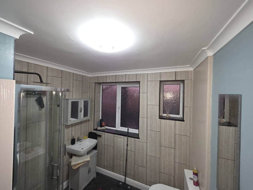 Main bathroom featuring shower cubicle with rain shower head, toilet, storage cupboards, toiletries