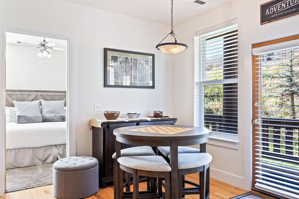 A bright dining nook featuring a round table and plush seating, perfectly situated beside large windows and a private balcony door. A cozy space for enjoying breakfast or dinner with a view.