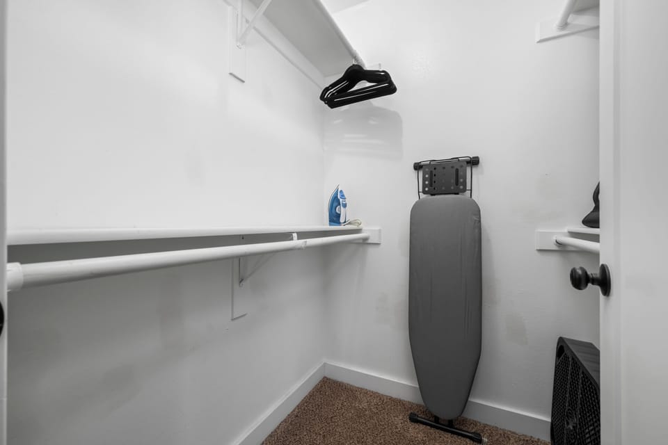 Spacious walk-in closet with hangers, iron, and ironing board