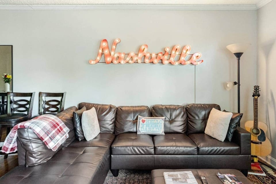 Step into comfort with this cozy living room, perfect for relaxing after a day exploring Nashville! Enjoy the plush sectional with soft pillows and a warm blanket, while soaking in the Music City vibes and strumming a favorite tune on the six string.