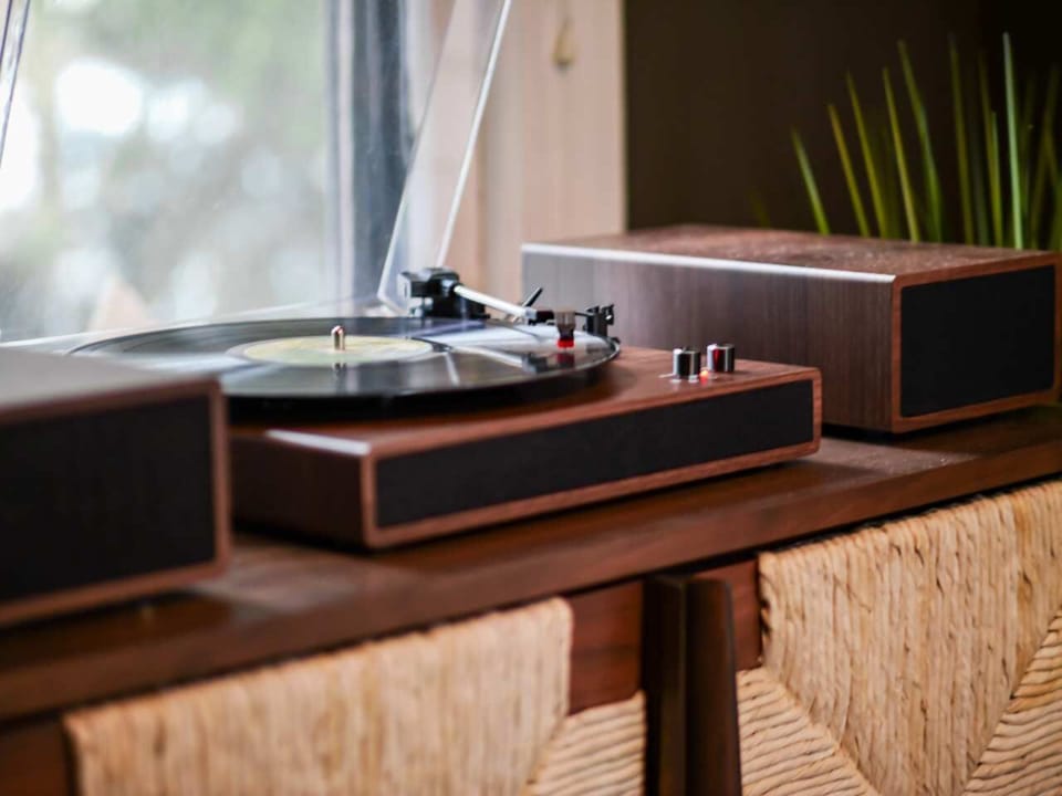 Vintage record player setup w/ speakers on a wood console, ready for relaxing vinyl listening
