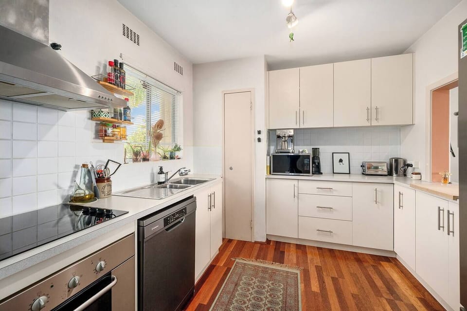 The kitchen is fully equipped with modern appliances, including an espresso machine, microwave, oven, stove, dishwasher, and rice cooker, inviting guests to cook and gather with ease.