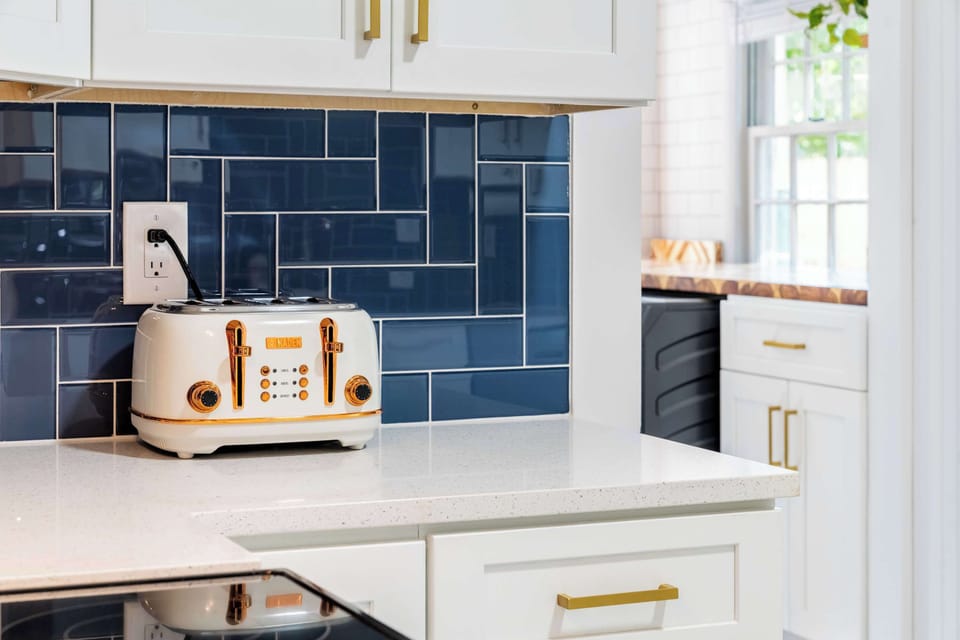 Modern chef’s kitchen featuring a vibrant cobalt backsplash, sleek white cabinetry, and high-end gold accents.